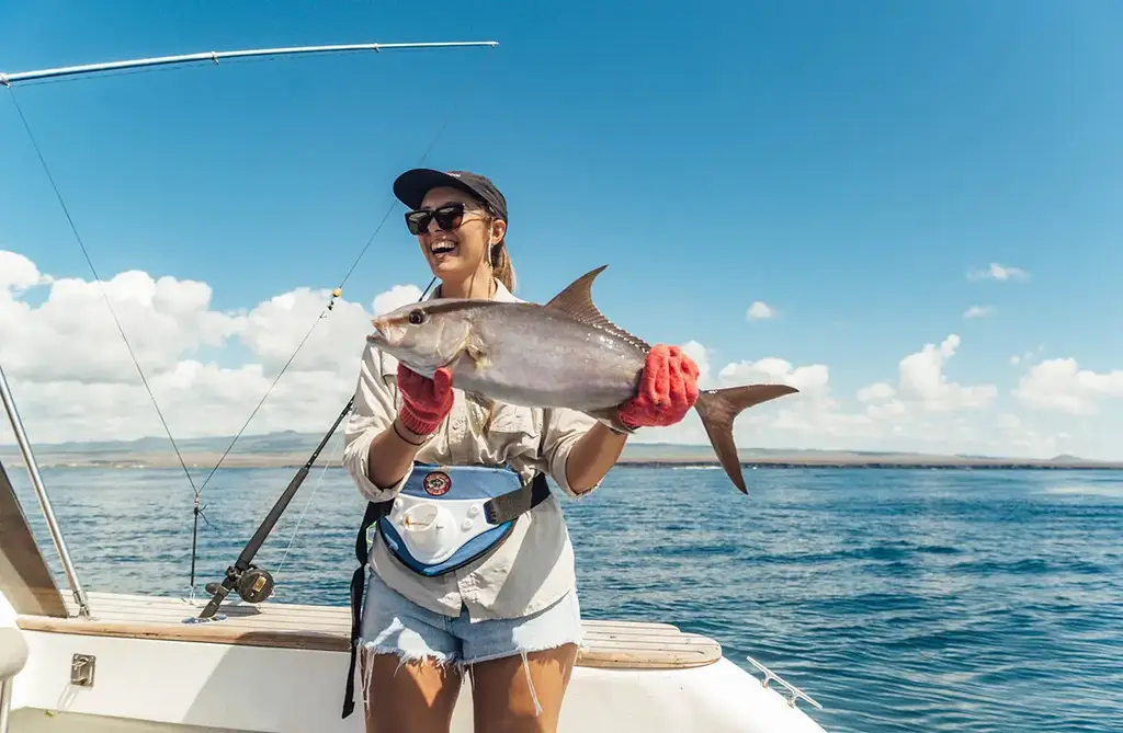 Guest holding a catch aboard a Galápagos fishing excursion