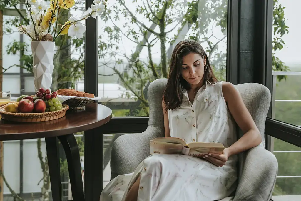 Guest reading by a window overlooking the forest