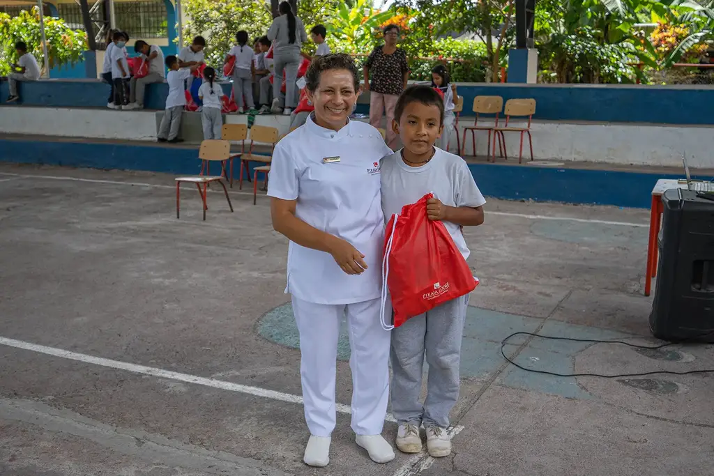 A lodge team member with a child holding a Pack for a Purpose bag